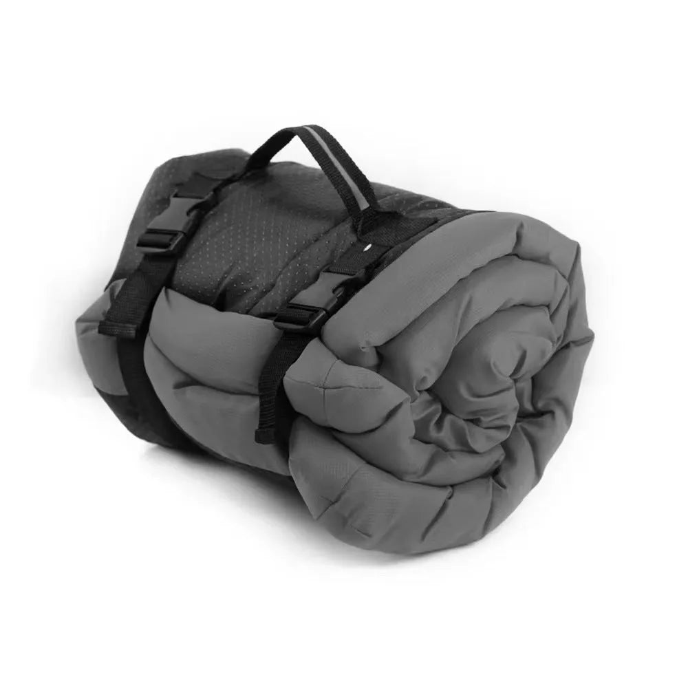 Blue folded portable dog bed with nylon buckles next to an unfolded bed on grass.