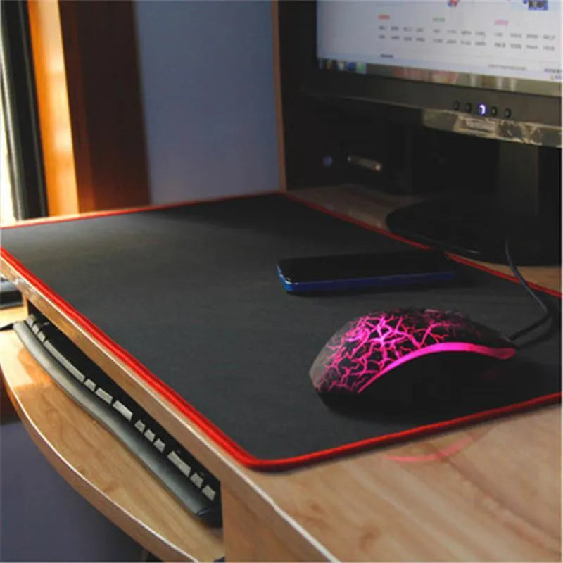 Oversized rubber mouse pad 30x60cm with stitched edges, black colour, on a desk with keyboard and mouse