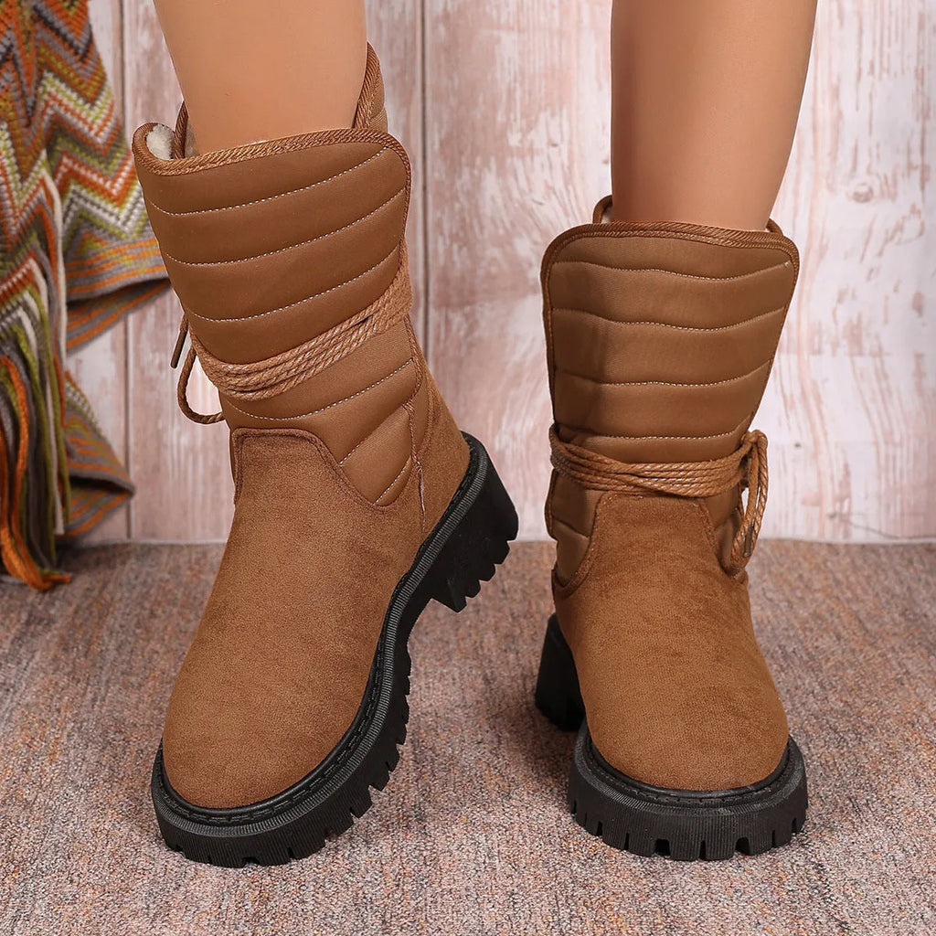 Women's black suede snow boots with chunky heel and lace-up design, shown on a foot.