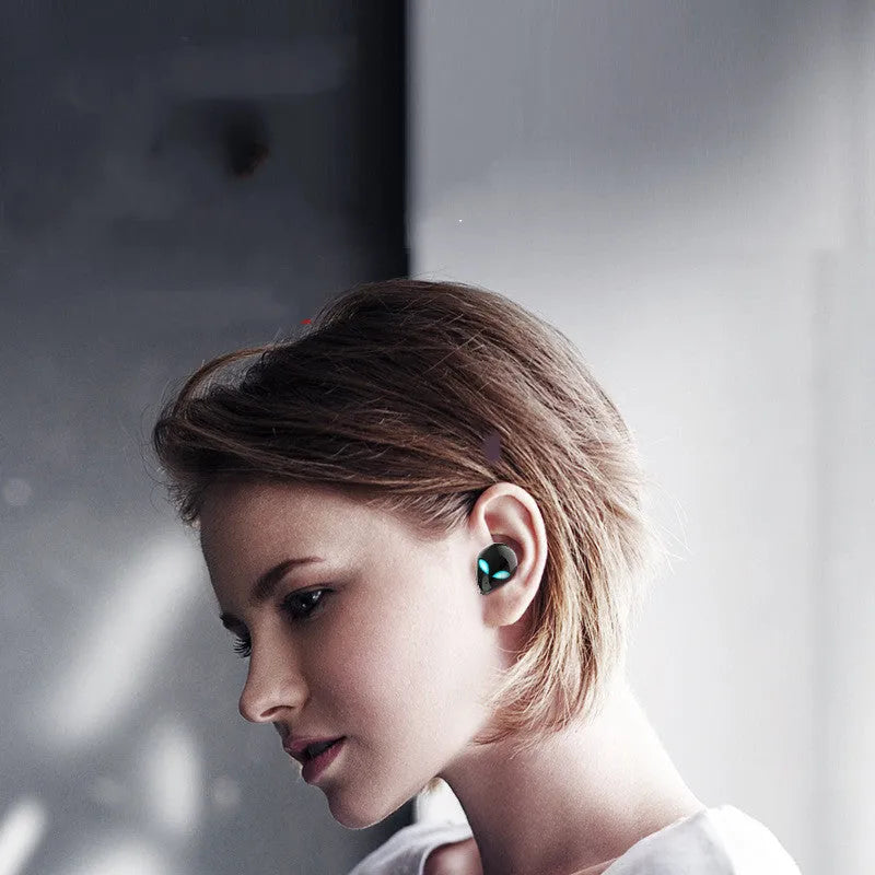 Creative Outer T8 Starman alien-design Bluetooth earbuds with red lighting next to wireless charging case.