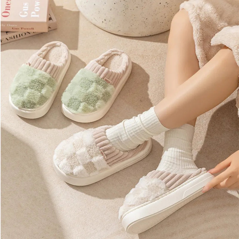 Women's plaid patterned coral velvet indoor slippers with a thick soft sole on a wooden floor.