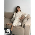 White women's floral print two-piece suit with bell sleeve top and wide leg pants on a hanger.