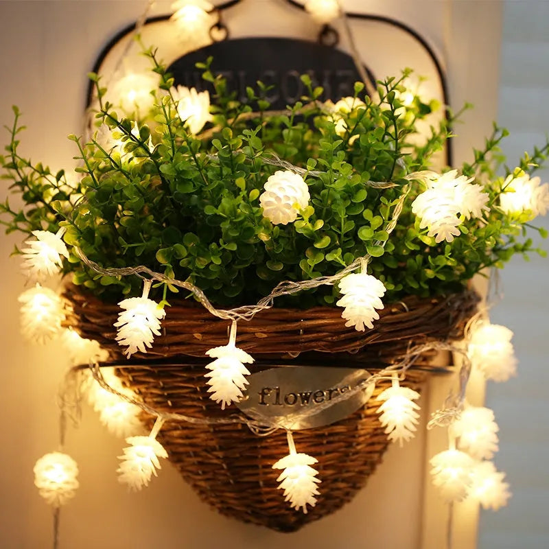 Warm white plastic pine cone LED light string powered by batteries on a dark background.