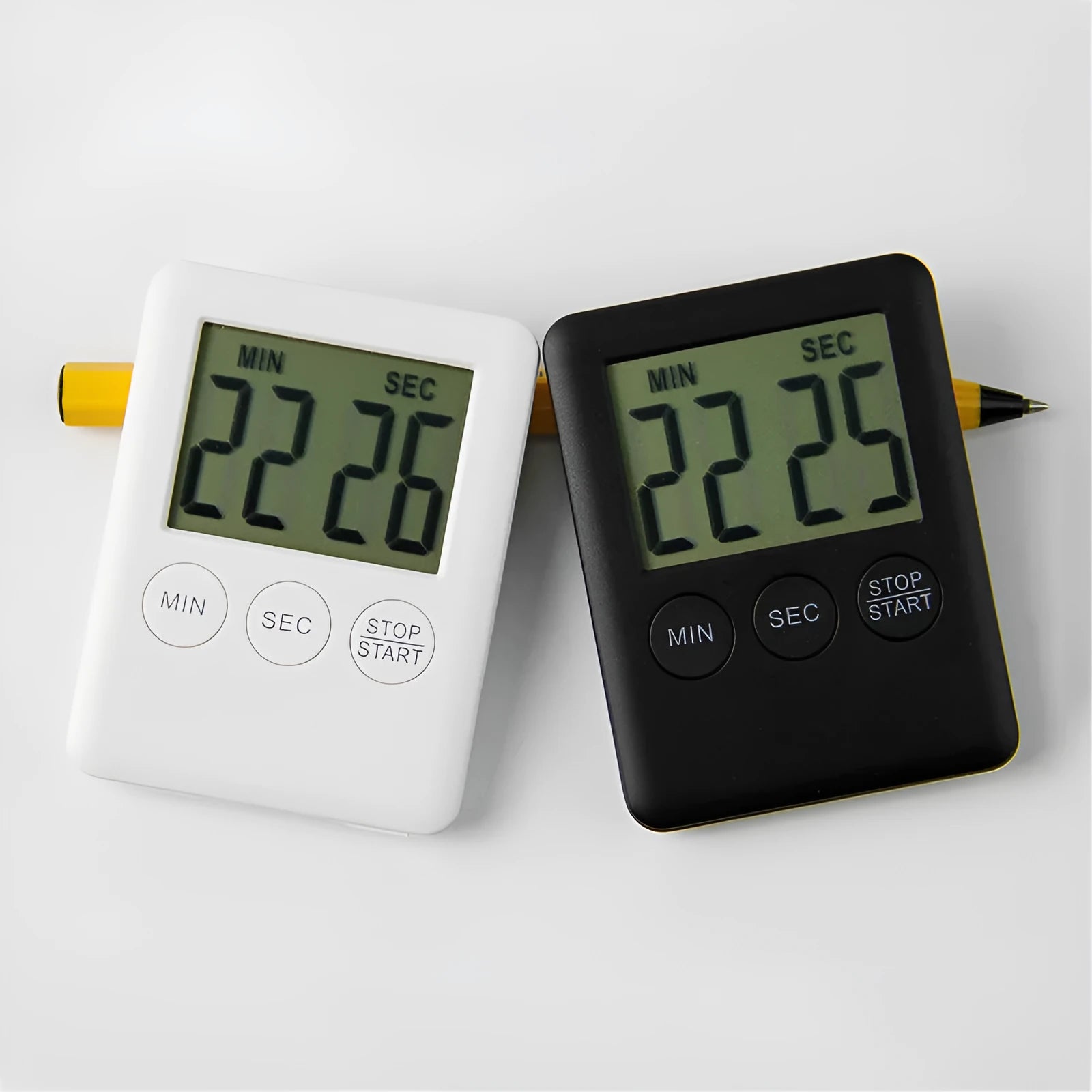 Black and white digital kitchen timer with LCD screen and magnetic back on a fridge