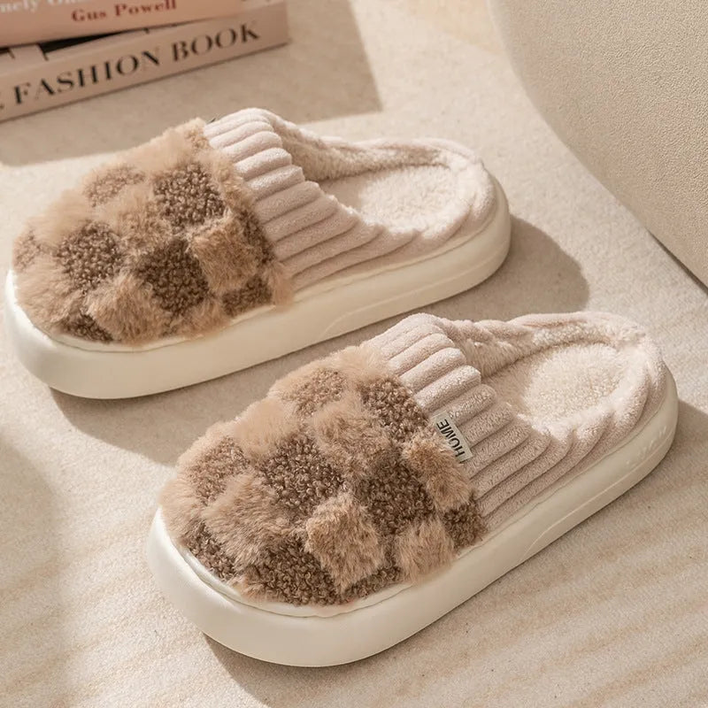 Women's plaid patterned coral velvet indoor slippers with a thick soft sole on a wooden floor.