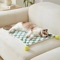 Green plaid pattern pet blanket with soft fleece texture on sofa