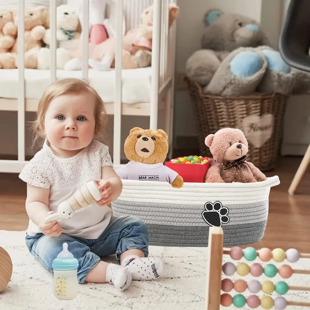Light beige handmade cotton rope woven storage basket with a wooden handle on a table.