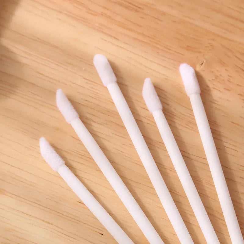 Pack of disposable lip brush applicators with flocked heads and black handles on a white background.