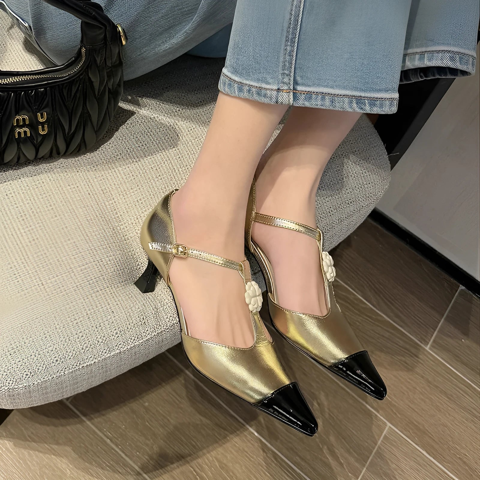 Women's black stiletto heel shoes with pointed toe, flower decoration, and buckle detail on sheepskin upper