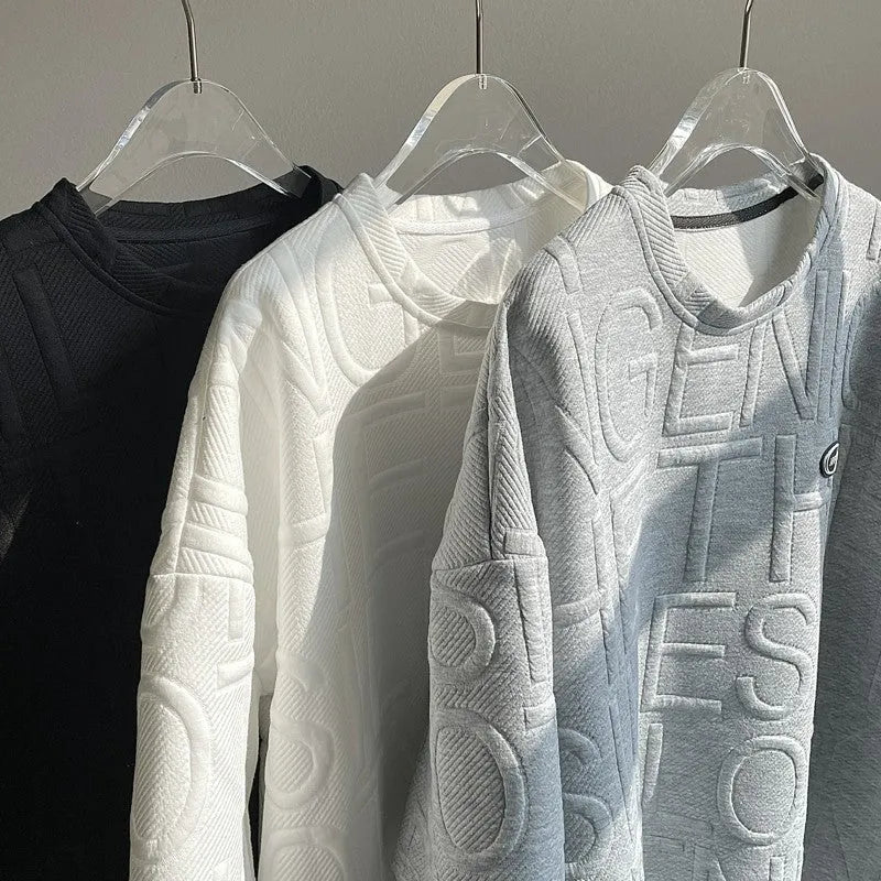 Man wearing a grey loose-fit T-shirt with a retro-style 3D raised letter print across the chest.