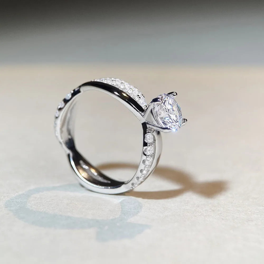 A geometric silver ring with a twisted band and a 1 carat moissanite stone in a four-claw setting.