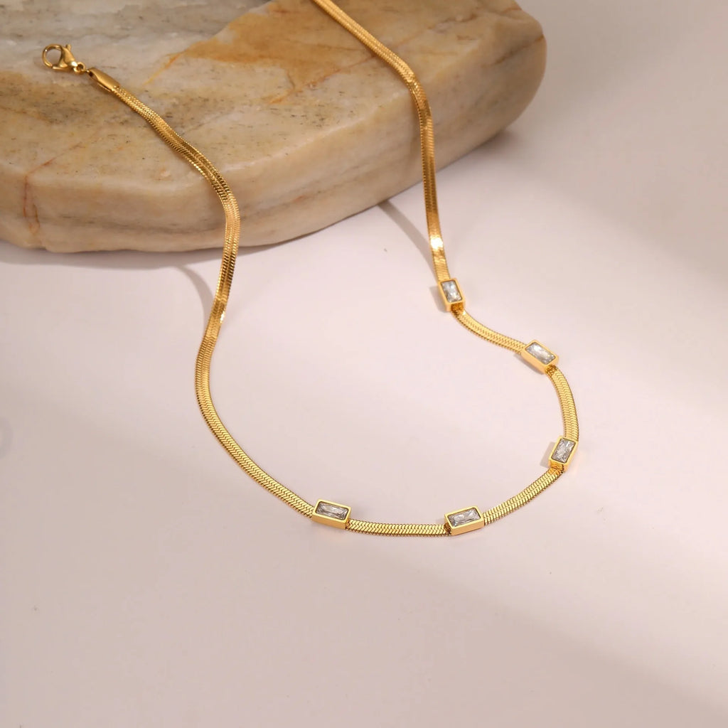 Gold geometric square zircon pendant necklace on a flat stainless steel snake chain.