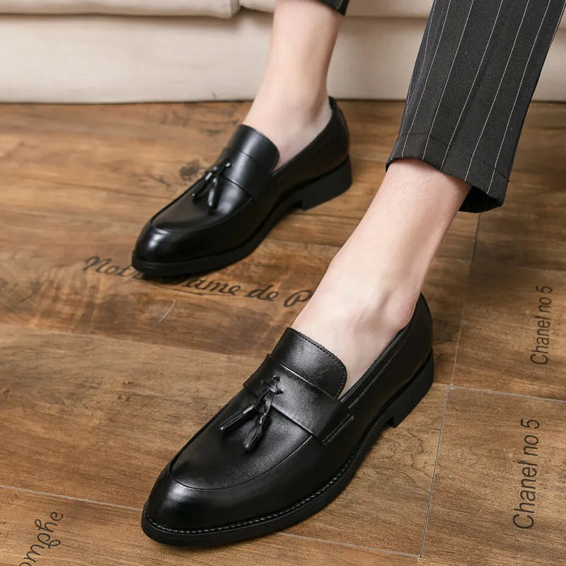 Men's black slip-on loafer with tassel detail and rubber sole on white background