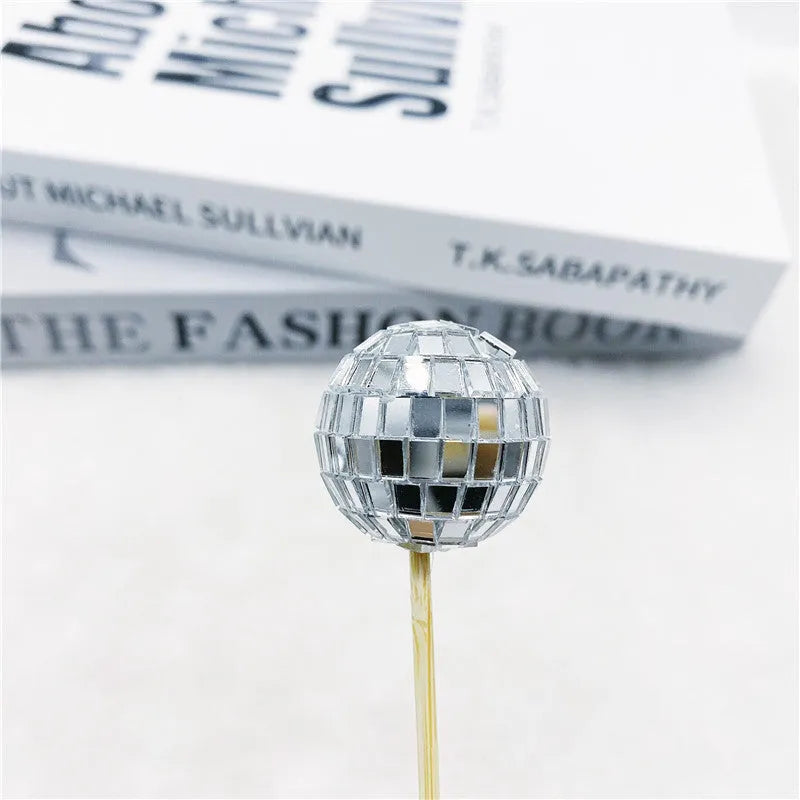 Glass disco ball cake decorations with wooden sticks in multiple sizes on birthday cake