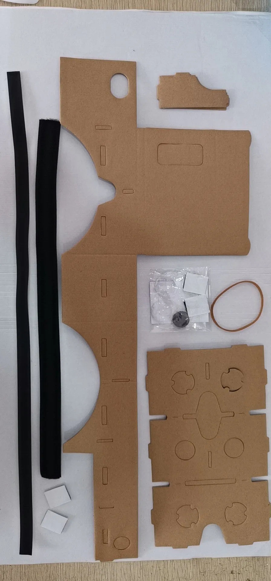 Foldable pink and white cardboard VR headset for smartphones with lenses and a head strap.