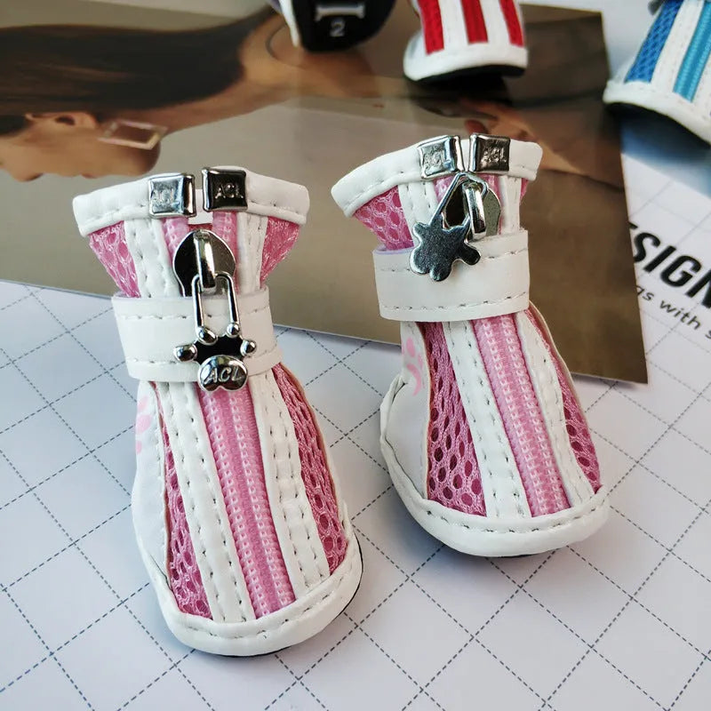 Four blue cloth dog shoes with zipper closures, showing non-slip soles, laid out on a white surface.