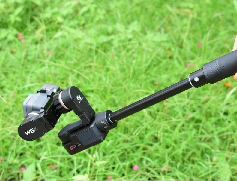 Black retractable selfie stick with Bluetooth remote, extended to full length with a smartphone attached.