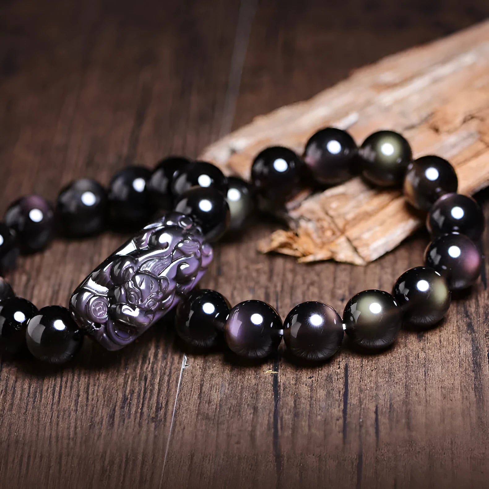 Natural icy obsidian crystal Pi Xiu bracelet with geometric beads on a white background.