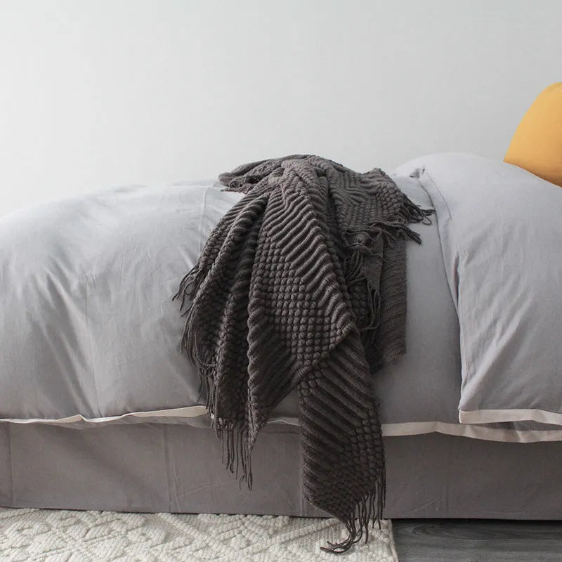 Small grey polyester nap blanket folded on a sofa, showing its texture and size.