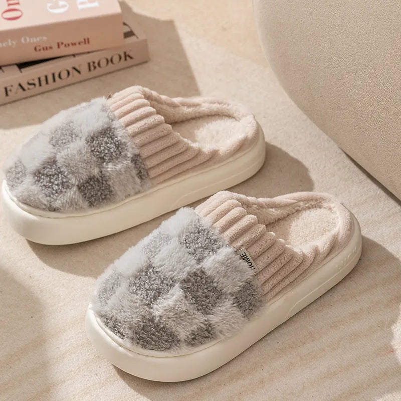 Women's plaid patterned coral velvet indoor slippers with a thick soft sole on a wooden floor.