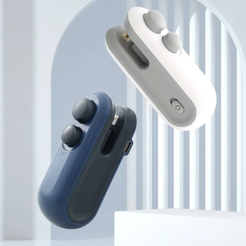 White handheld vacuum sealing machine with USB port and cutter blade on a kitchen counter.