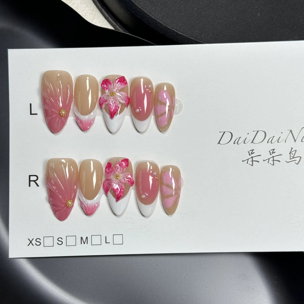 Set of French style artificial nails with white tips and 3D white lily flowers on almond-shaped plastic nail tips.