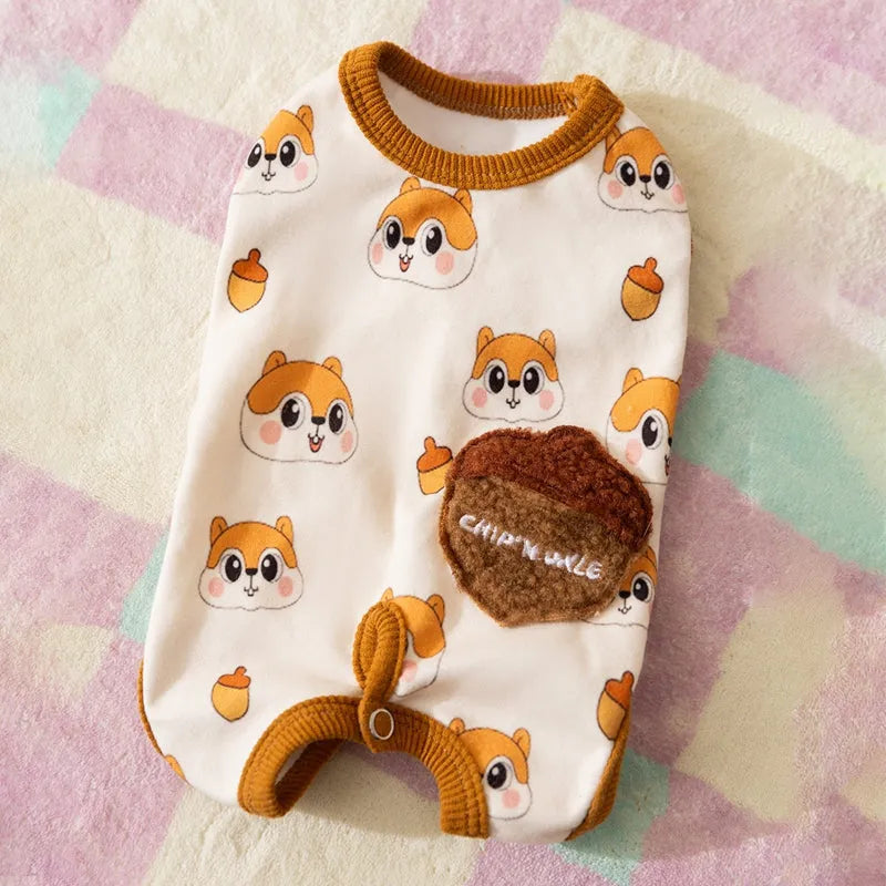 Small dog wearing Chip 'n' Dale themed cream onesie with yellow trim and embroidered acorn pocket