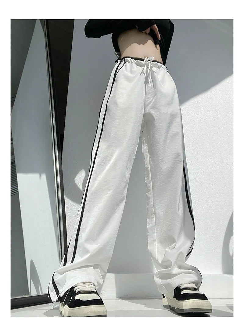 Women's navy blue loose straight-leg pants with white contrast ribbon parallel bars detail and low waist.