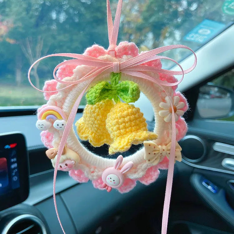 Handwoven wool bell orchid car pendant in green, hanging with dreamcatcher charm.