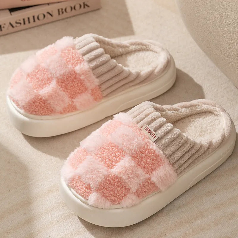 Women's plaid patterned coral velvet indoor slippers with a thick soft sole on a wooden floor.
