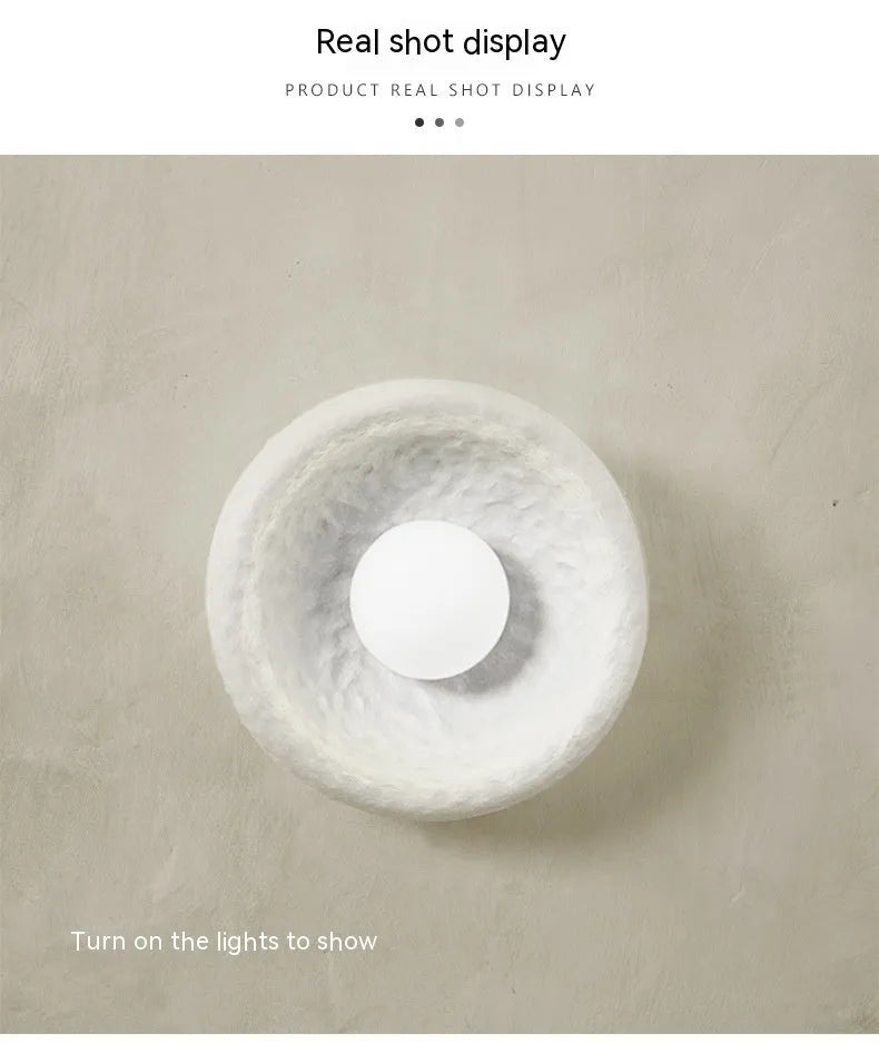 Japanese-style simple silent wall lamp with white resin shade on a wall.