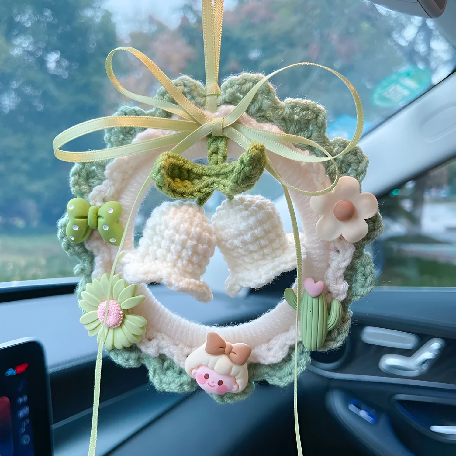 Handwoven wool bell orchid car pendant in green, hanging with dreamcatcher charm.