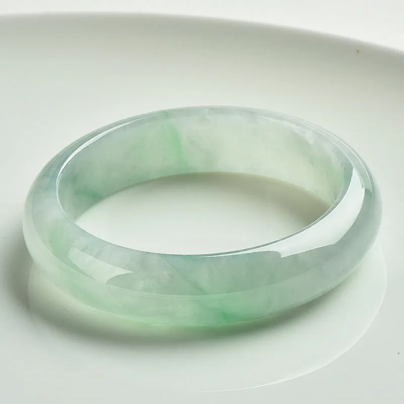 A light green jade bracelet for men and women, shown on a wrist, with a natural stone texture.