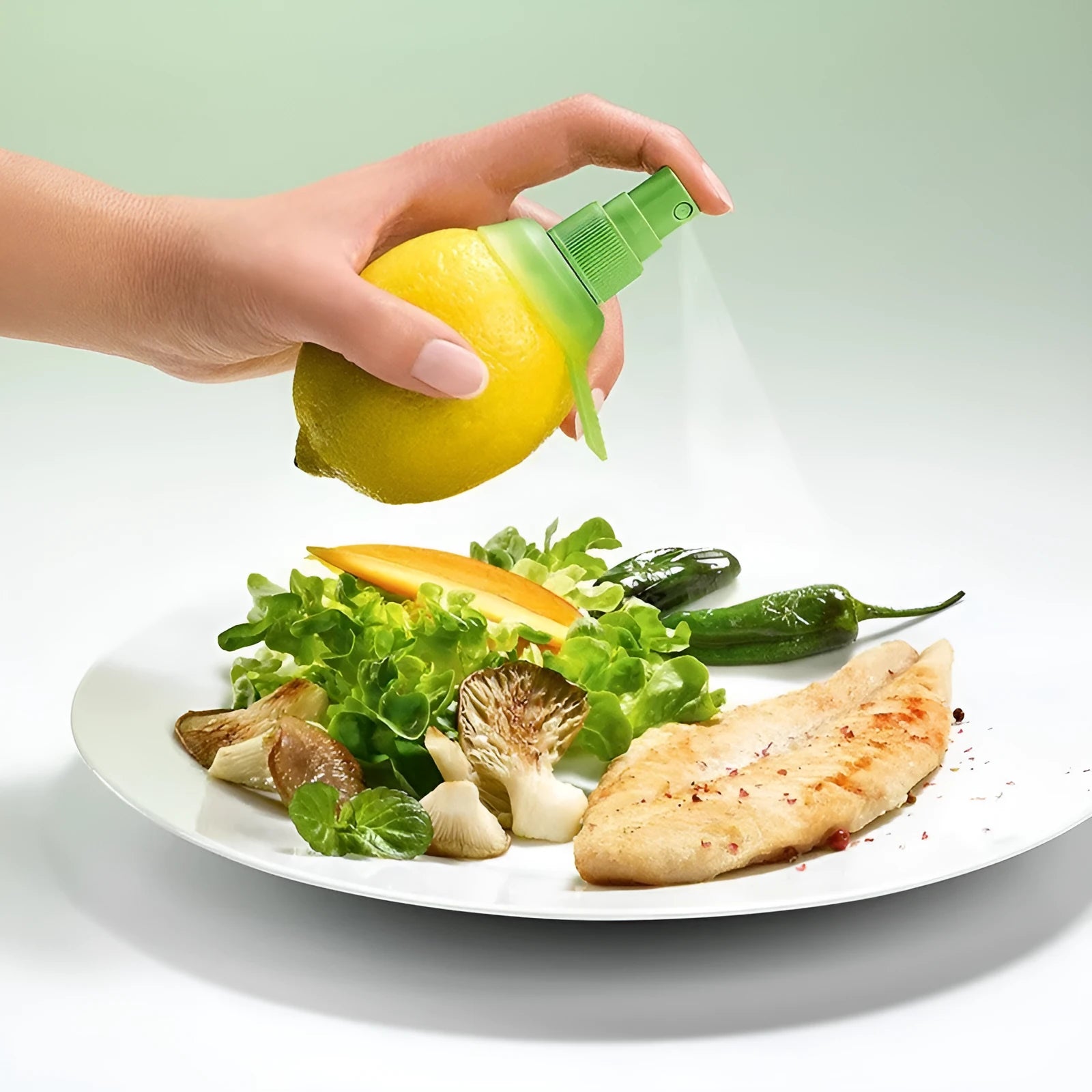 Green plastic lemon sprayer juice dispenser with screw-in nozzle on a white background