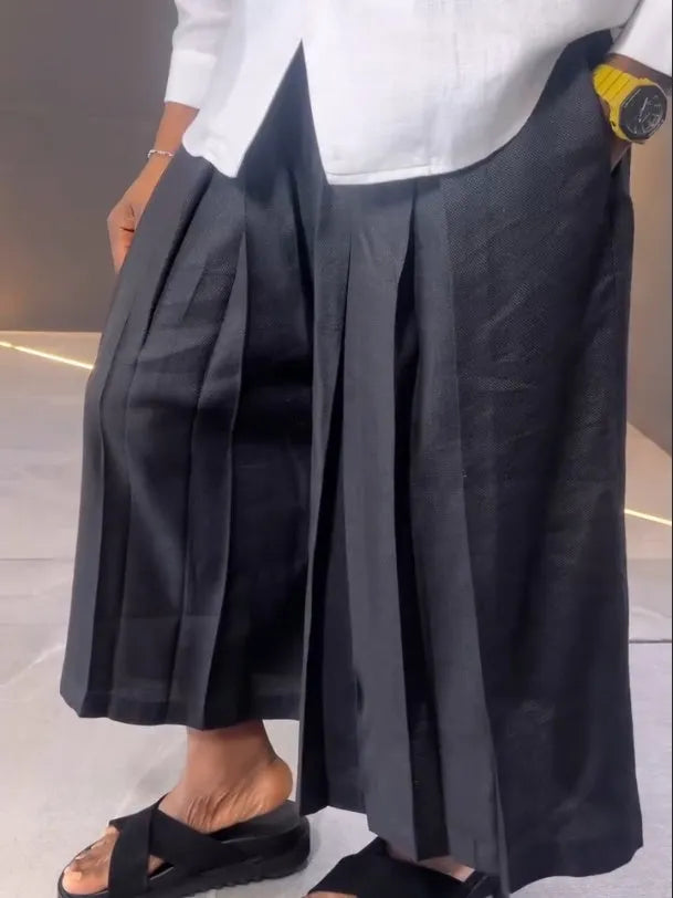 Women's white asymmetrical long sleeve shirt and black pleated trousers casual co-ordinates set on a hanger.