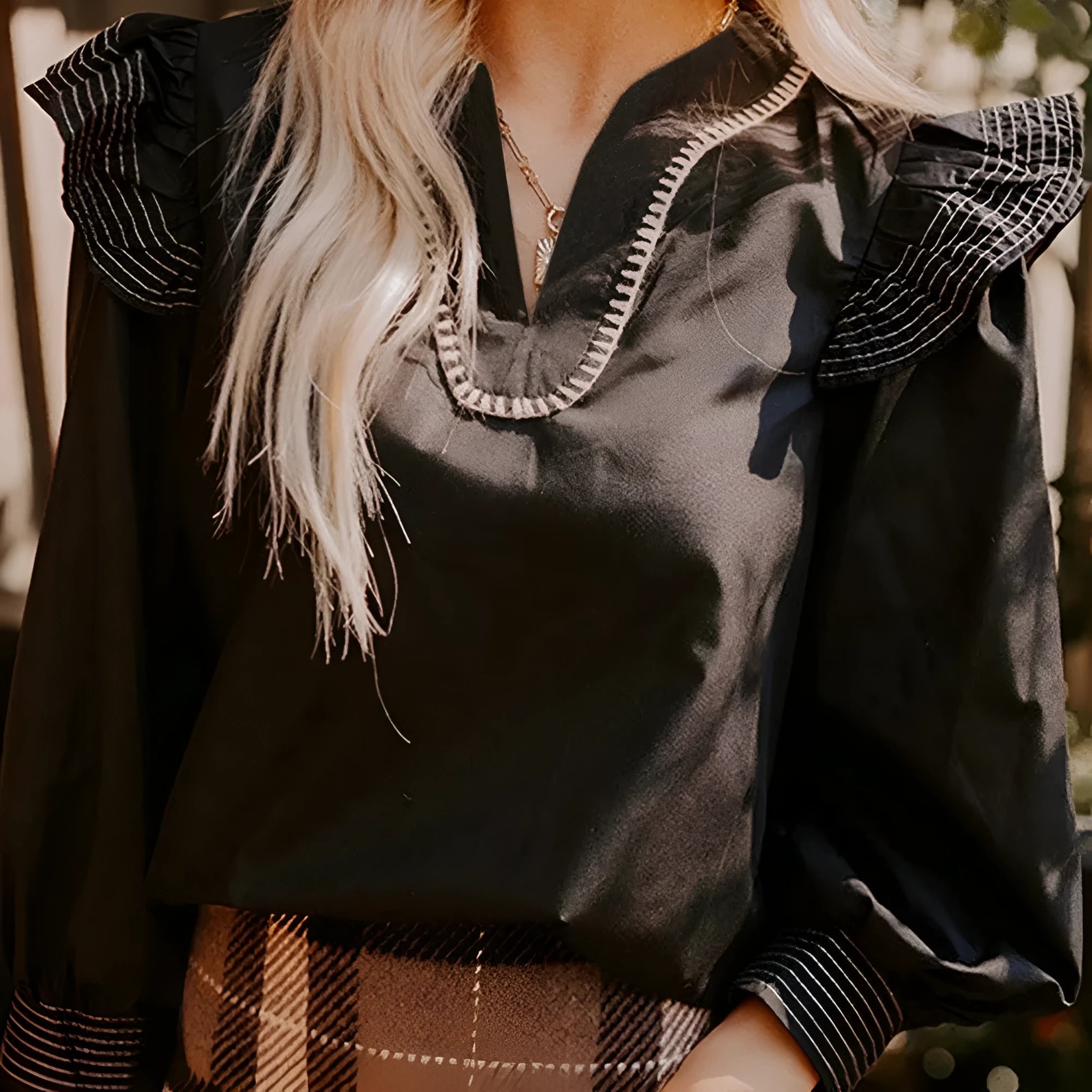 Black women's V-neck blouse with long ruffle sleeves and contrast stitching.