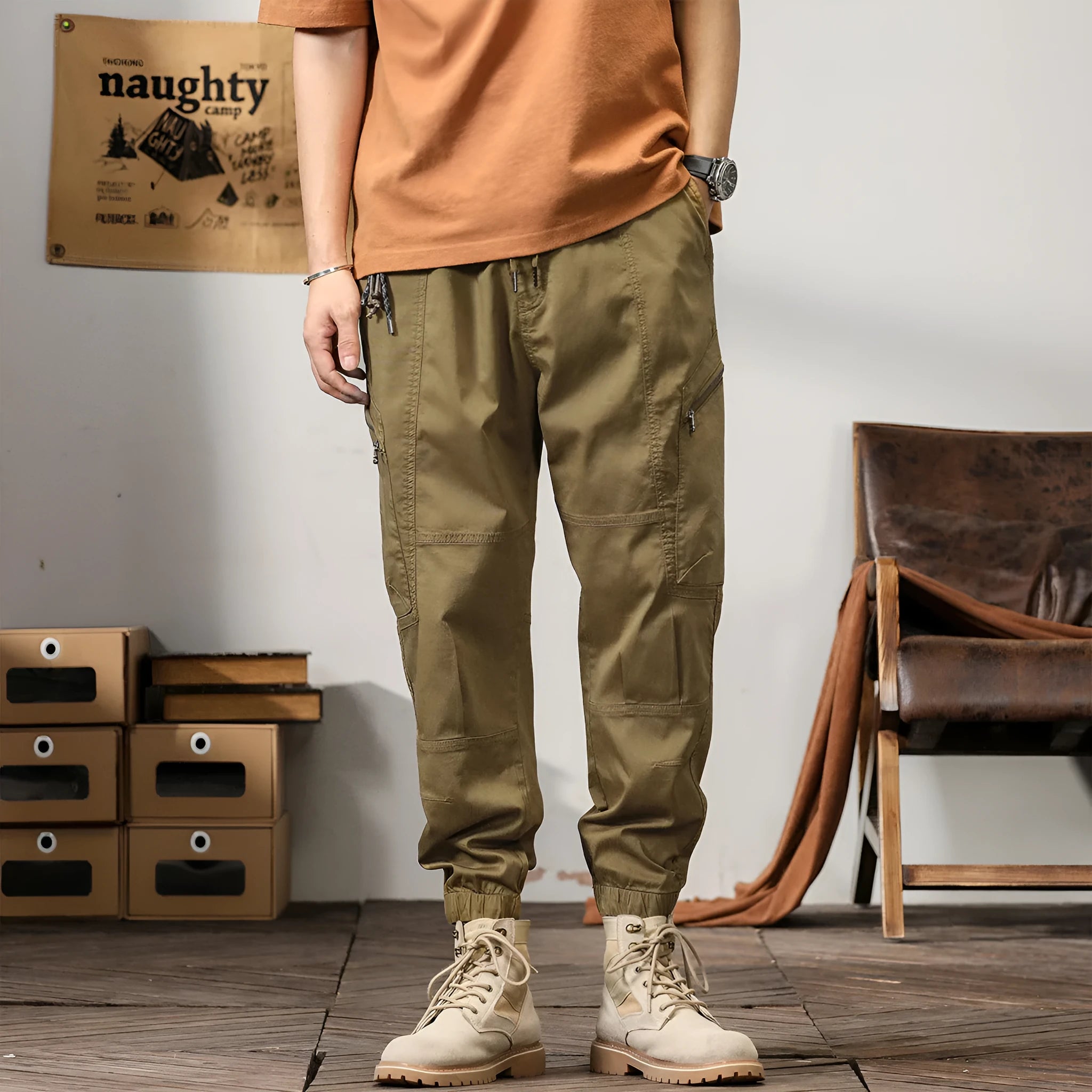 Men's khaki cotton tapered harem pants with ankle bands and a zip fly, laid flat.