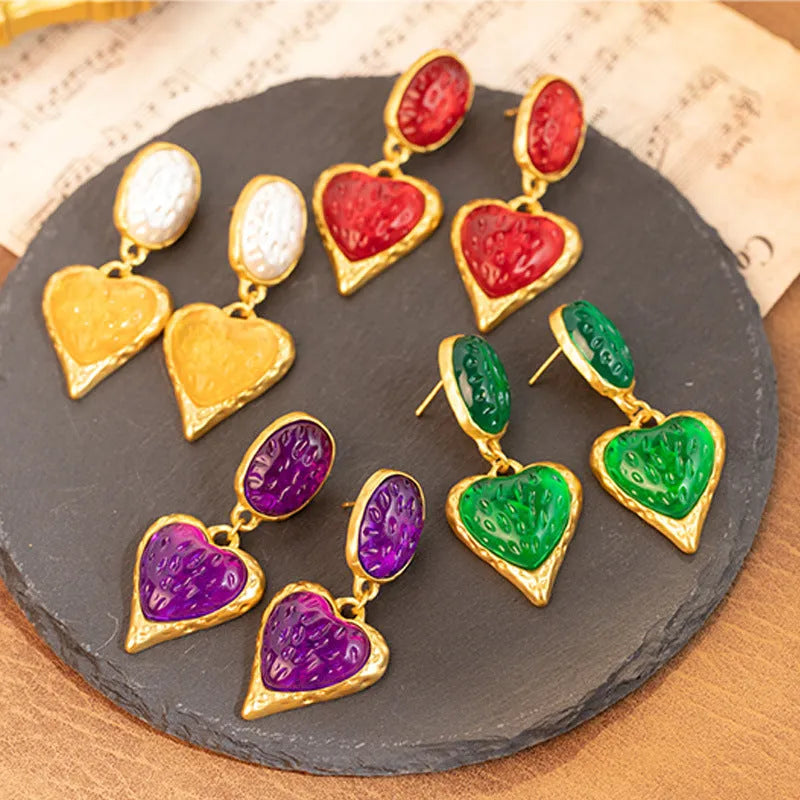 A pair of alloy silver needle pleated oval love heart stud earrings on a purple background.