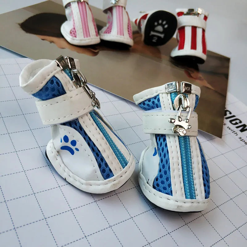 Four blue cloth dog shoes with zipper closures, showing non-slip soles, laid out on a white surface.