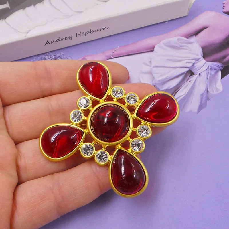 Close-up of a detailed baroque cross brooch with crystal accents on a zinc alloy base.