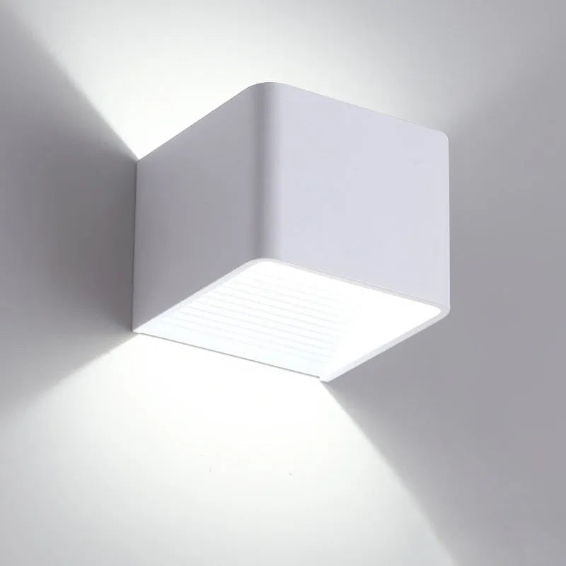 Square LED indoor wall lamp in black die-cast aluminium with warm white light on a wall