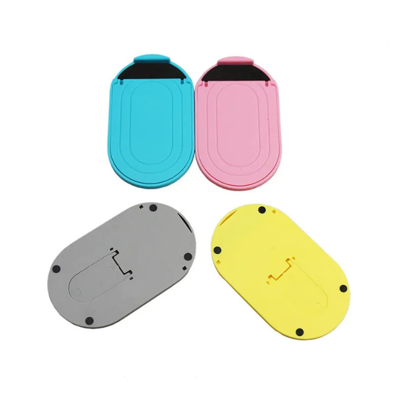 Plastic lazy bracket mobile phone stand in six colour options on a desk.