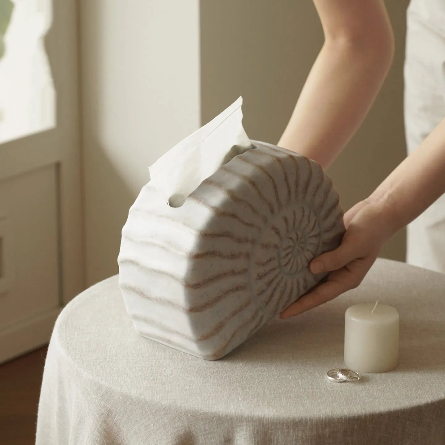 Solid resin conch-shaped tissue box cover in a natural colour on a table.