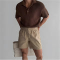 A pair of loose-fitting cotton sports shorts in khaki colour on a white background.