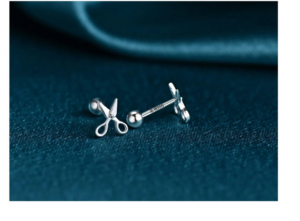 Silver screw-back ear nail with a small scissor charm for cartilage piercing.