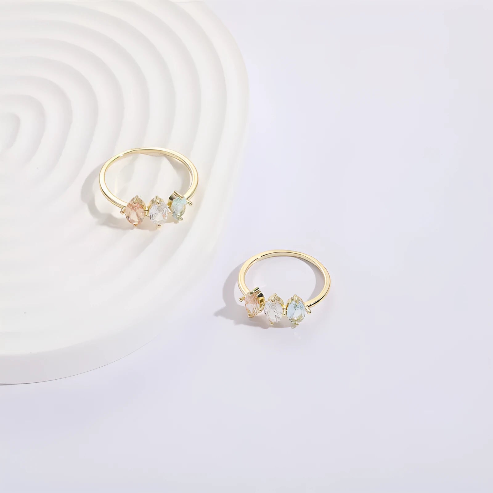 Geometric triangle birthstone ring with horse eye design and tricolour zircon stones on woman's hand