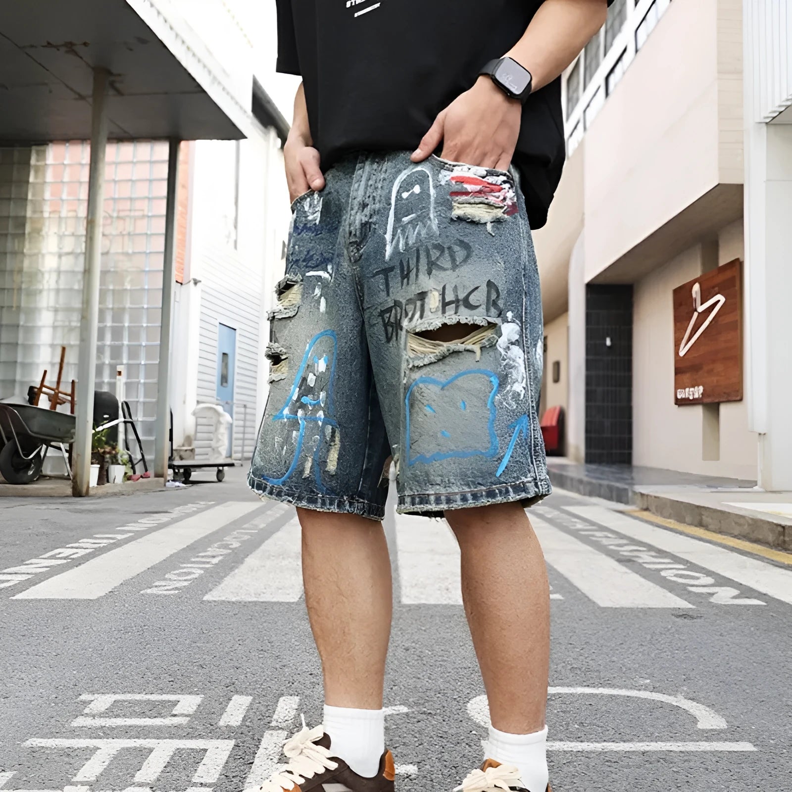 Blue ripped men's denim shorts with graffiti pattern and straight-leg cut.