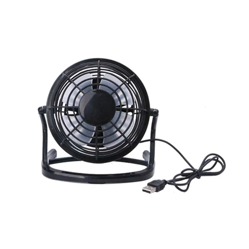 Compact black mini USB desk fan with adjustable tilt, placed next to a laptop.