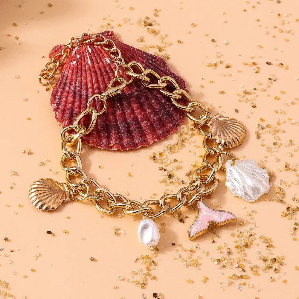 Women's white pearl alloy shell pearl mermaid tail bracelet on neutral background