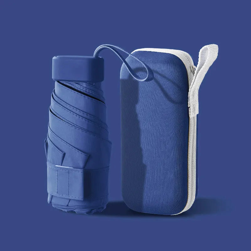 Ultra-light six-fold sun umbrella open, showing NC fabric canopy and rubber handle, next to its compact folded size in a capsule box.